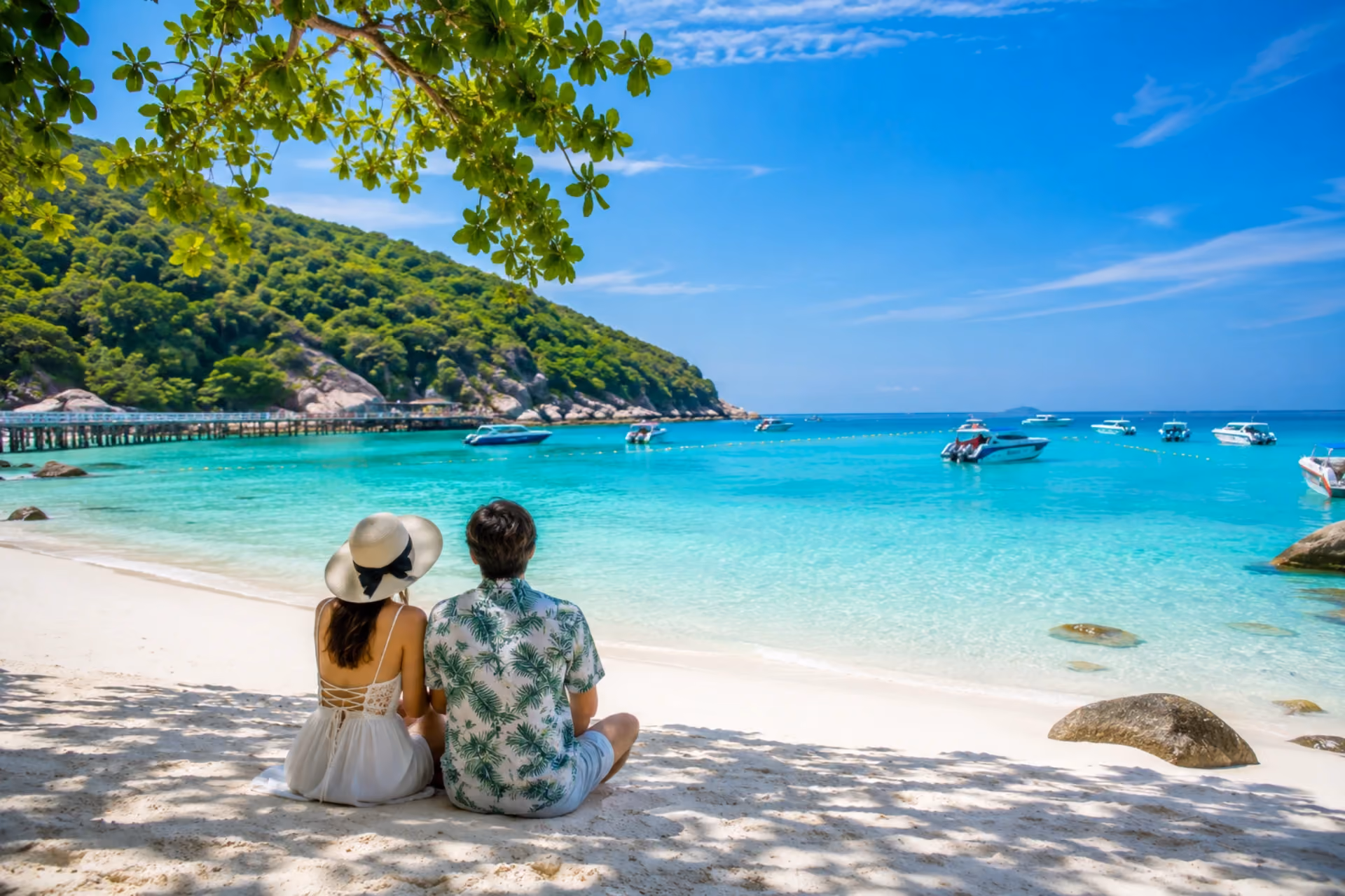 Couple relaxing on the white sands of Coral Island with turquoise water and boats in Pattaya