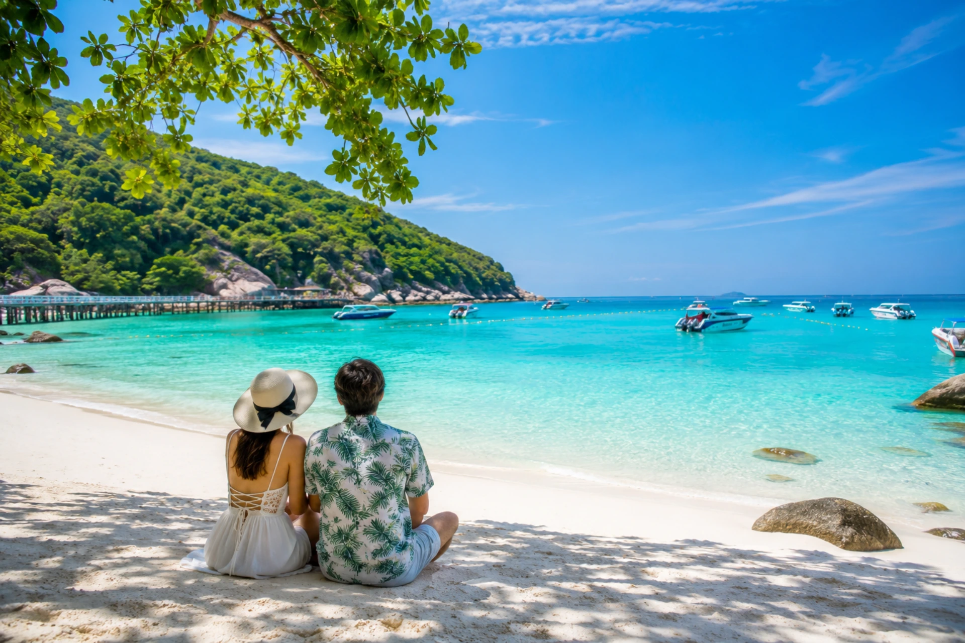 Couple relaxing on the white sands of Coral Island with turquoise water and boats in Pattaya