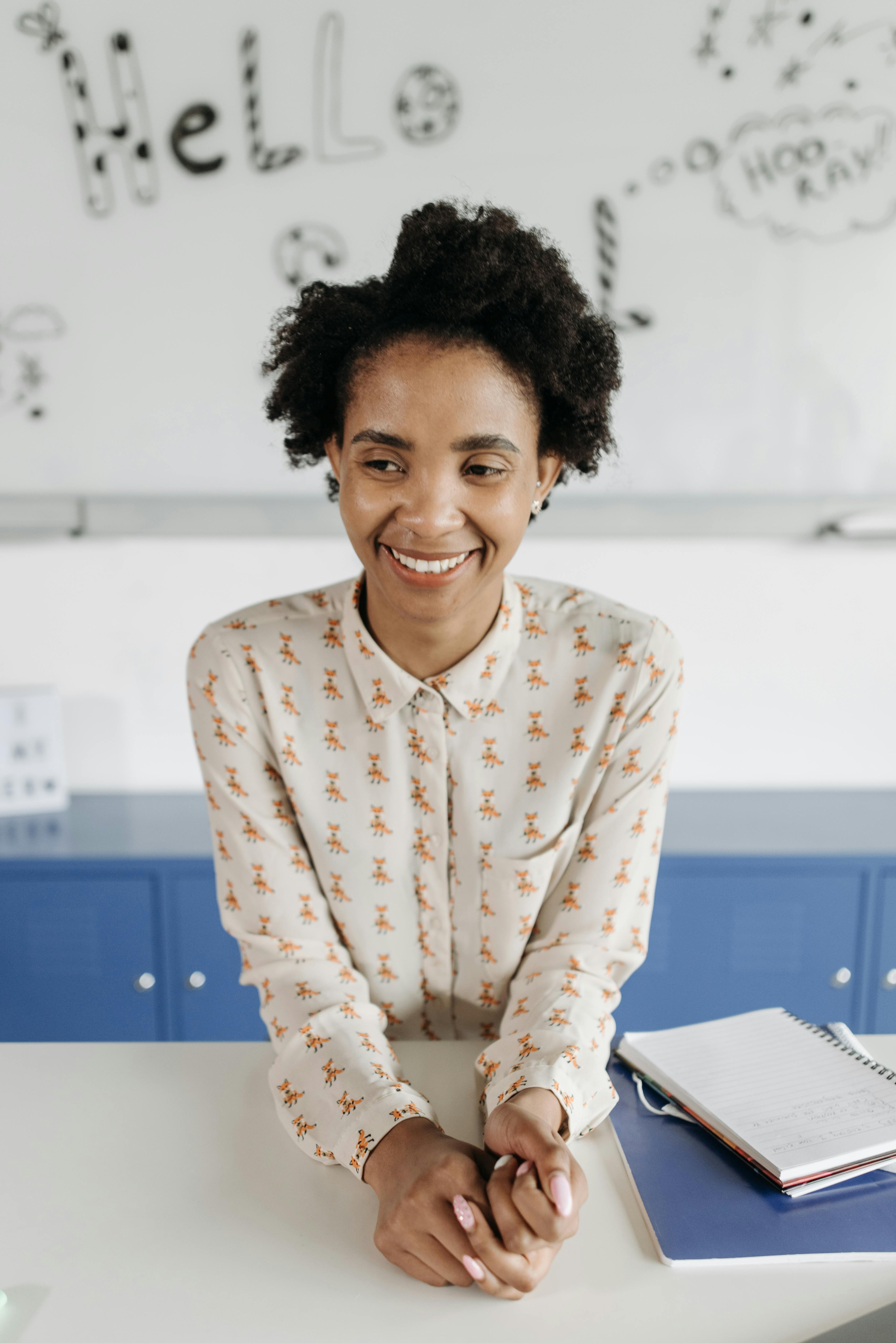 Ms Banks smiling at her desk in a classroom