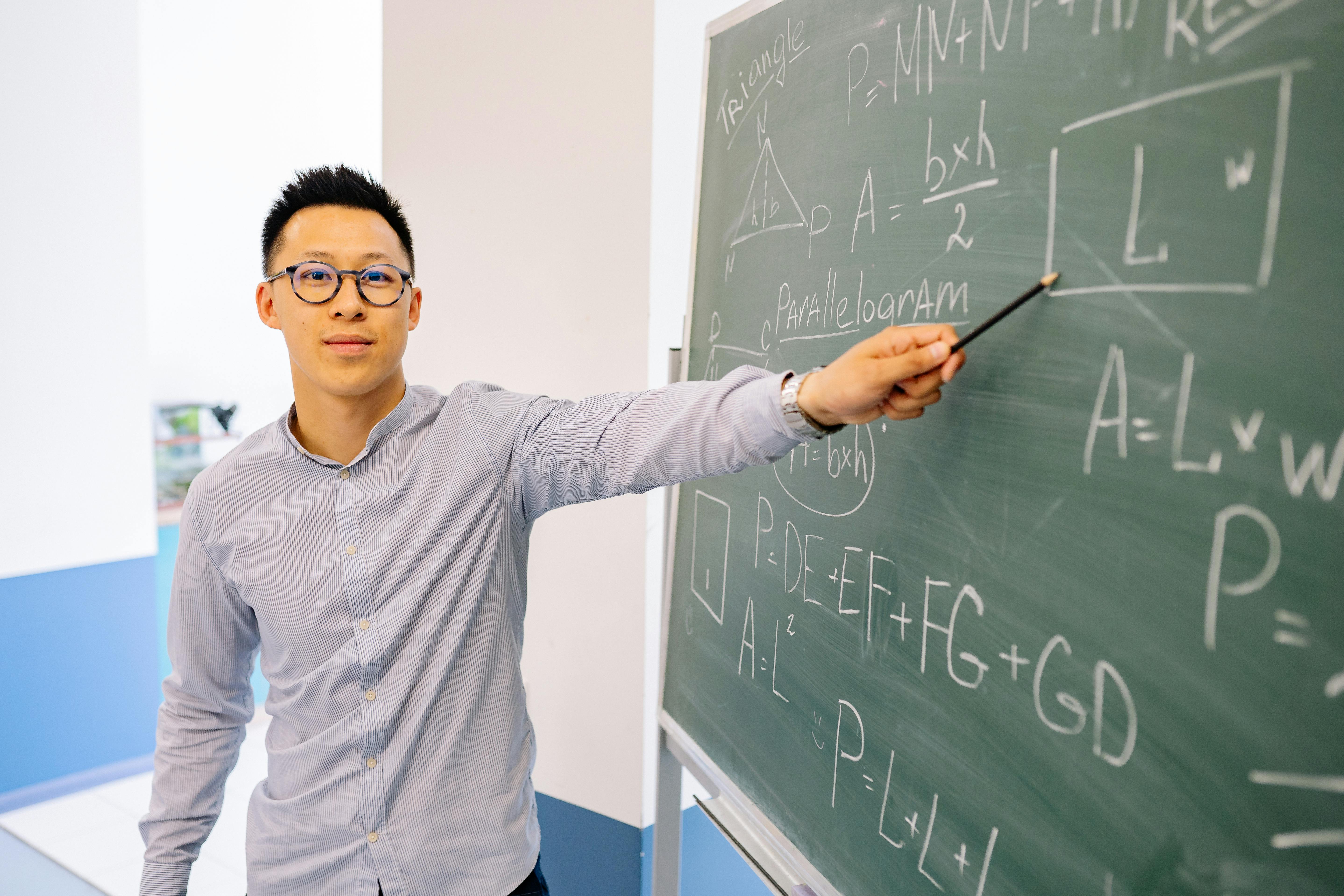 Math teacher pointing to geometry formulas on a chalkboard