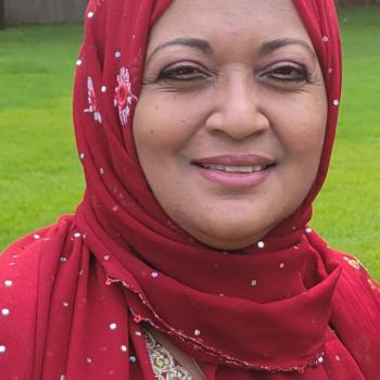 Bilquees Akhtar smiling outdoors in red hijab