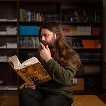 Staff member Alasdair Bulmer reading a book in library