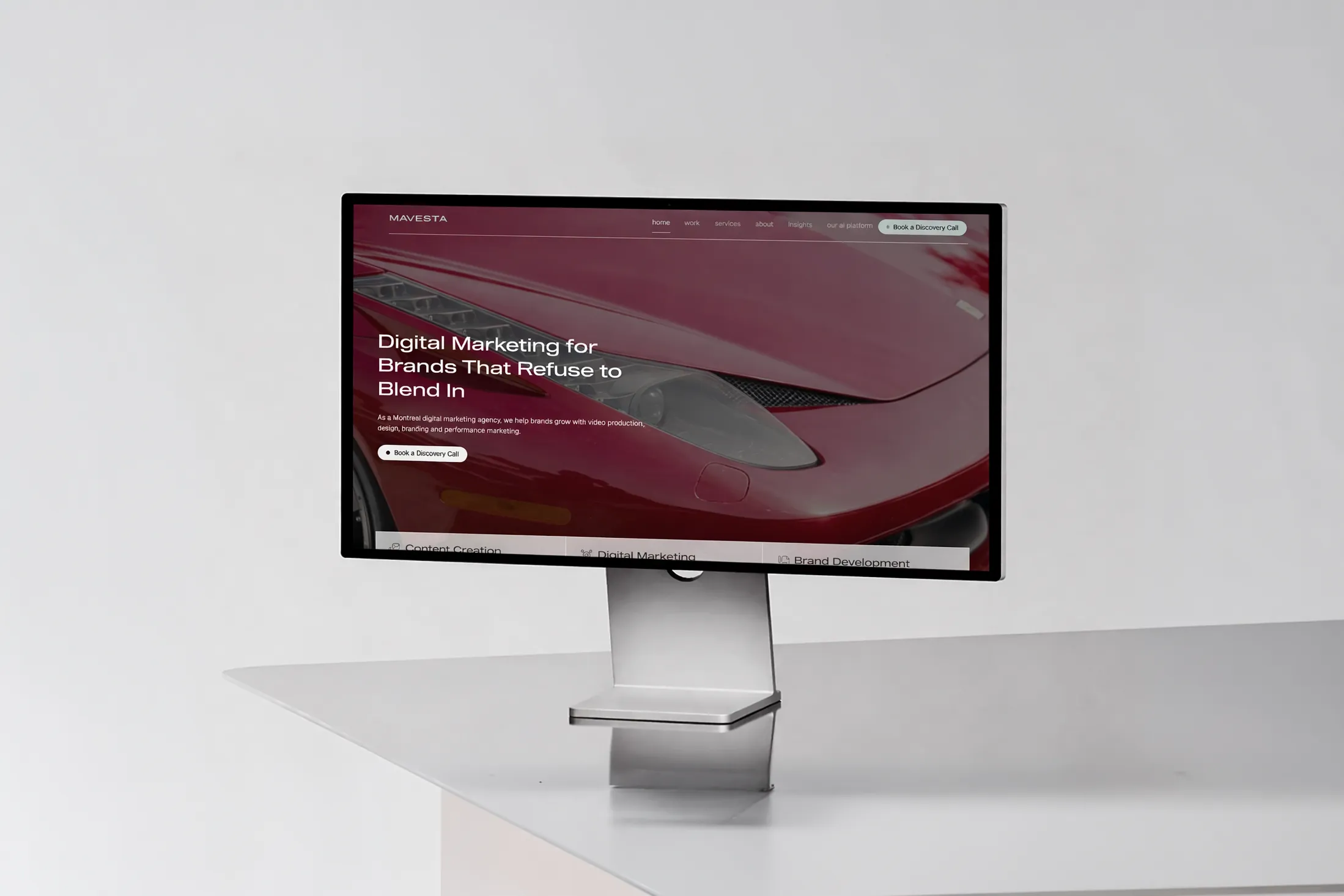 Computer monitor on a white desk displaying a digital marketing website with a red sports car background.