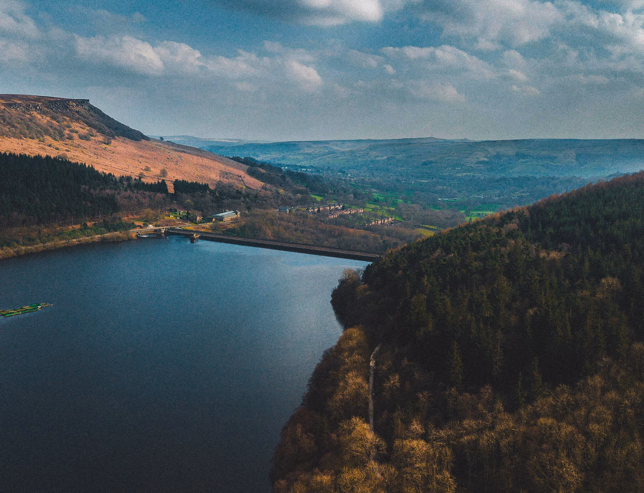 A large body of water surrounded by a lush green hillside.