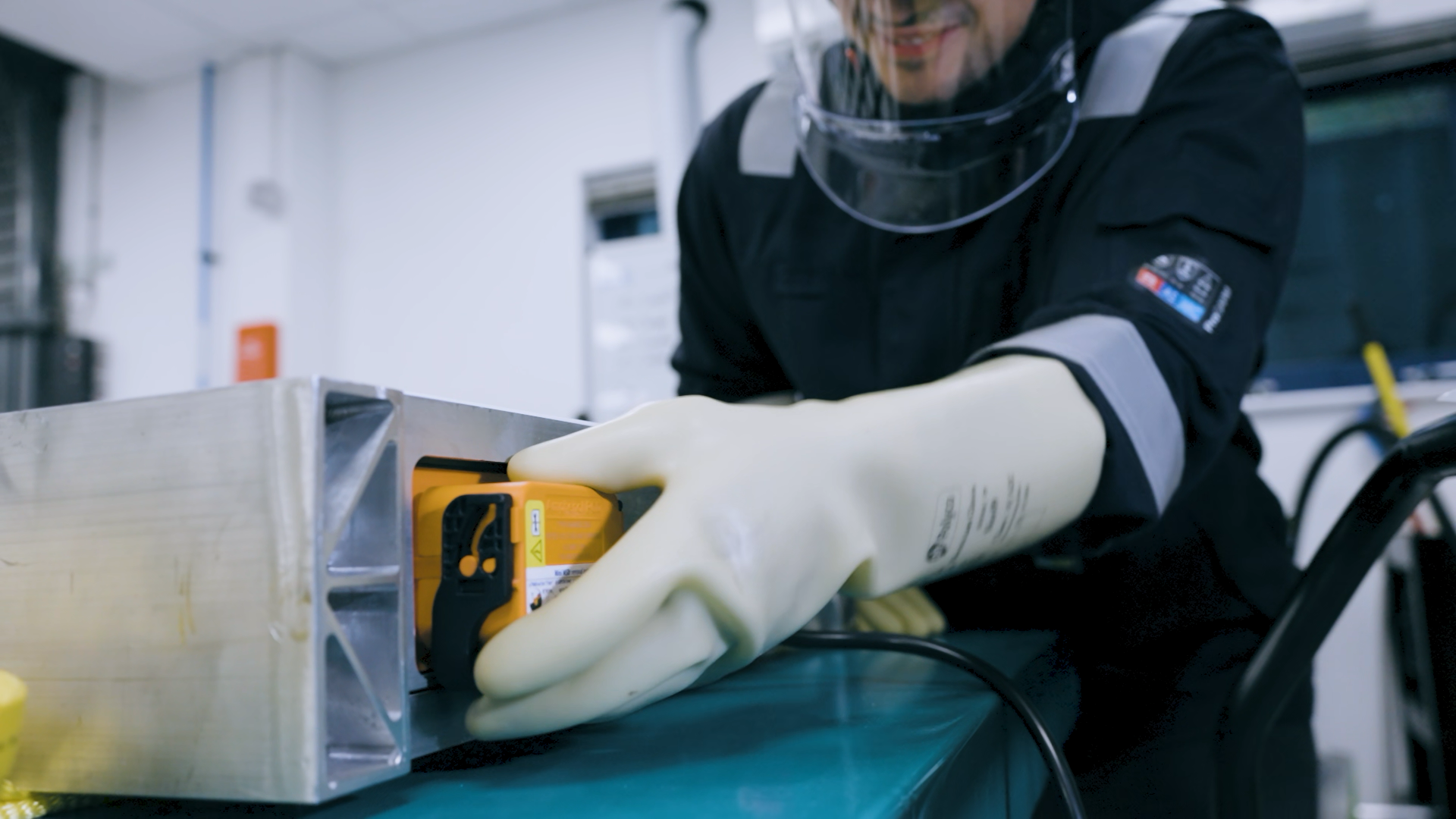 Rectangular electric vehicle battery pack with black cells and orange connectors.