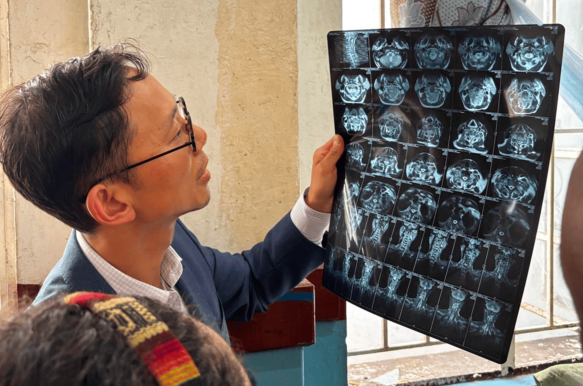 A Mission:Brain physician examines spinal and cranial X-rays while speaking with a patient, highlighting the hands-on care and diagnostic work being done during the Guadalajara mission.
