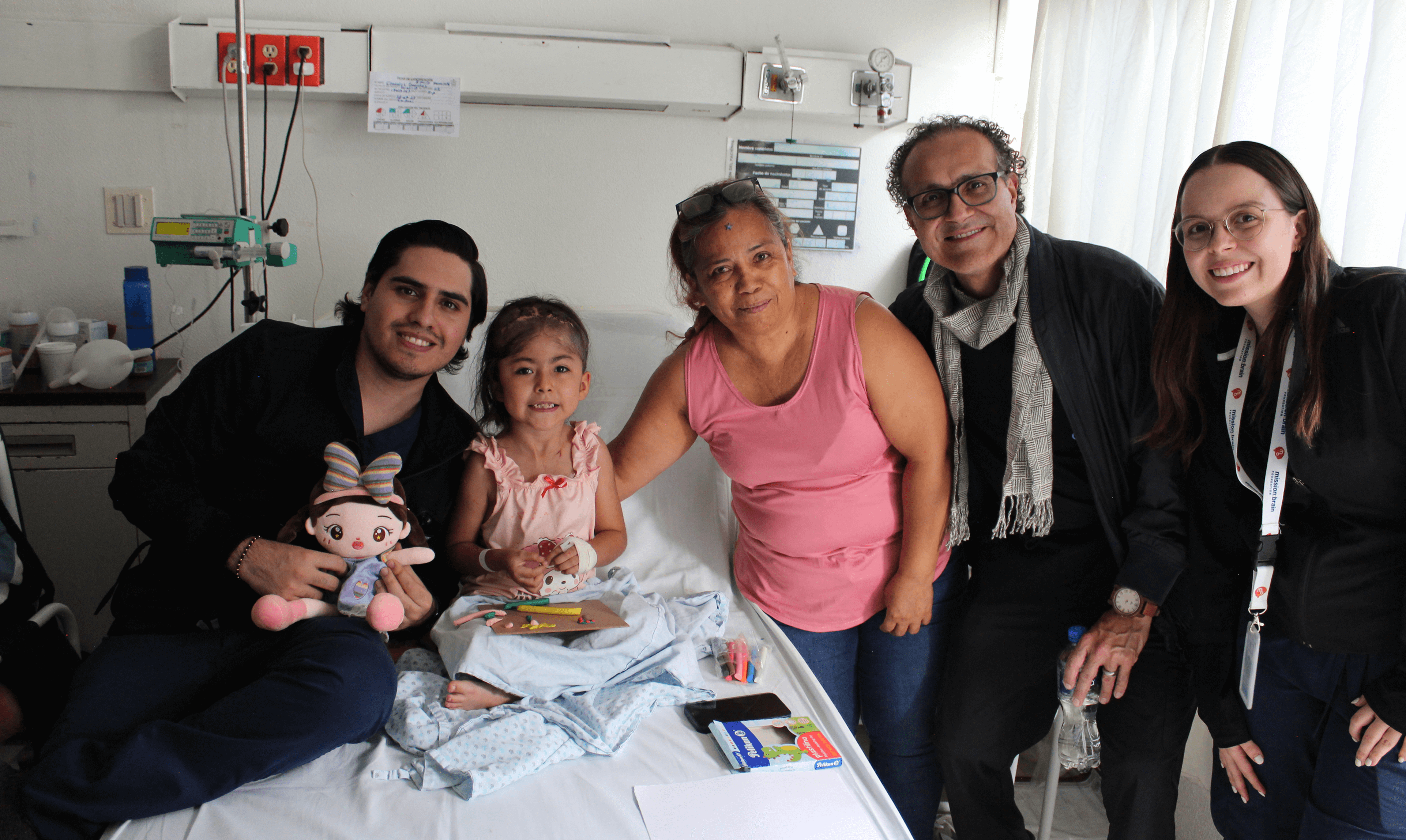 A young child paints with bright orange, wearing a shirt with a brain design—capturing the joy behind Mission:Brain’s arts and crafts day for pediatric patients in Guadalajara.