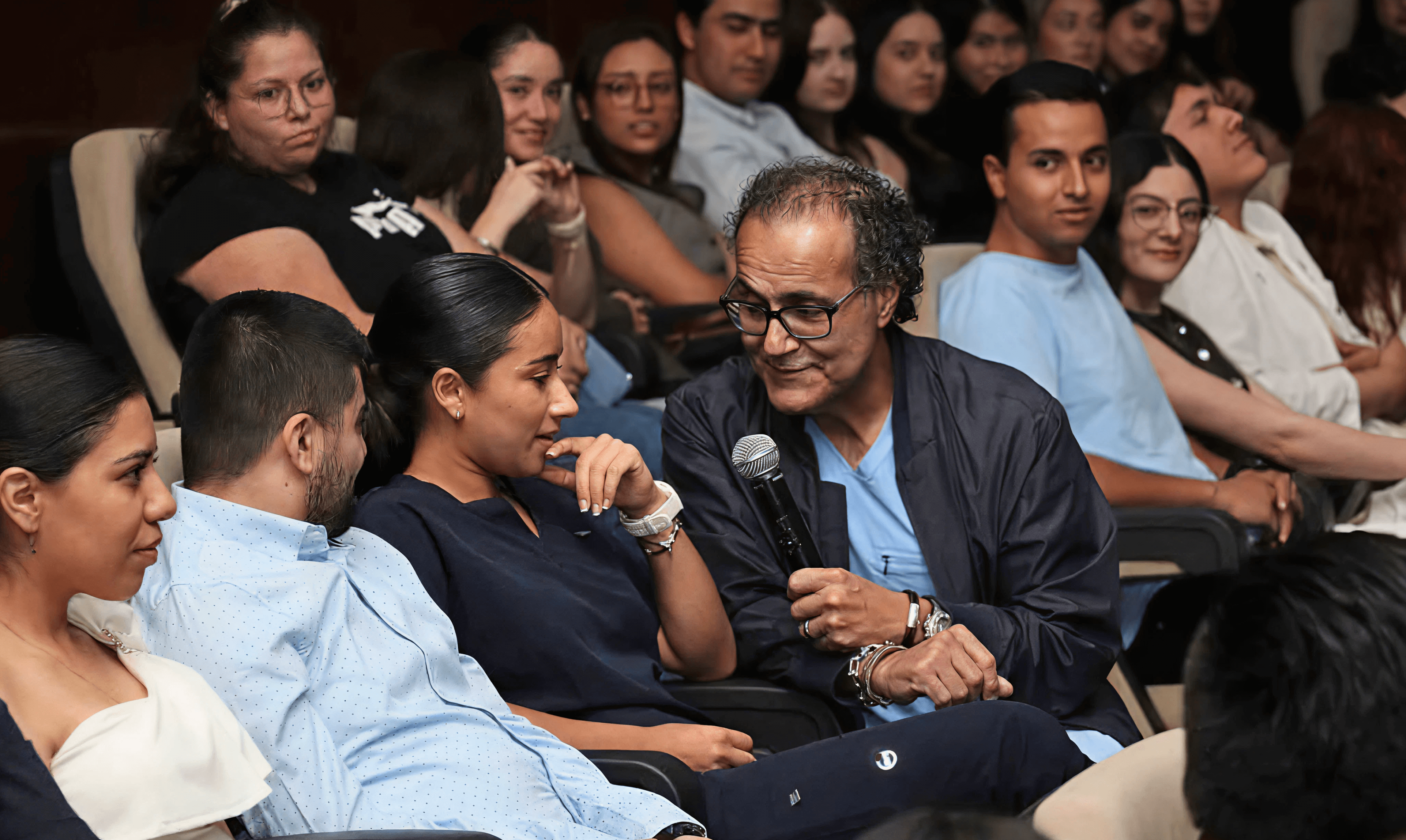 A young patient smiles in bed while proudly showing her drawing, joined by two Mission:Brain volunteers—capturing a joyful moment of connection and creativity during the Guadalajara outreach.