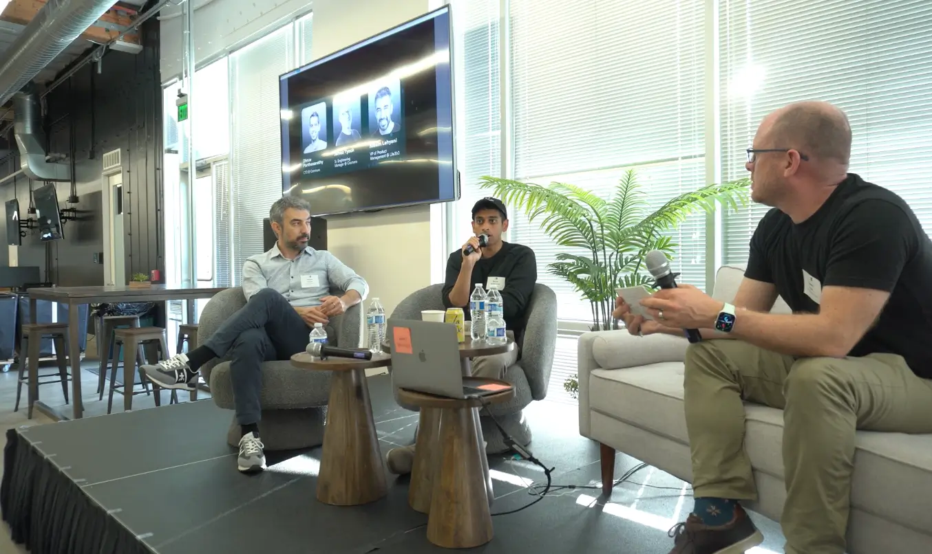 Three people speaking in a panel discussion with microphones in an office setting