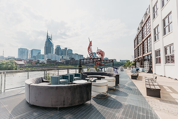 Outdoor rooftop lounge with city skyline and river view.