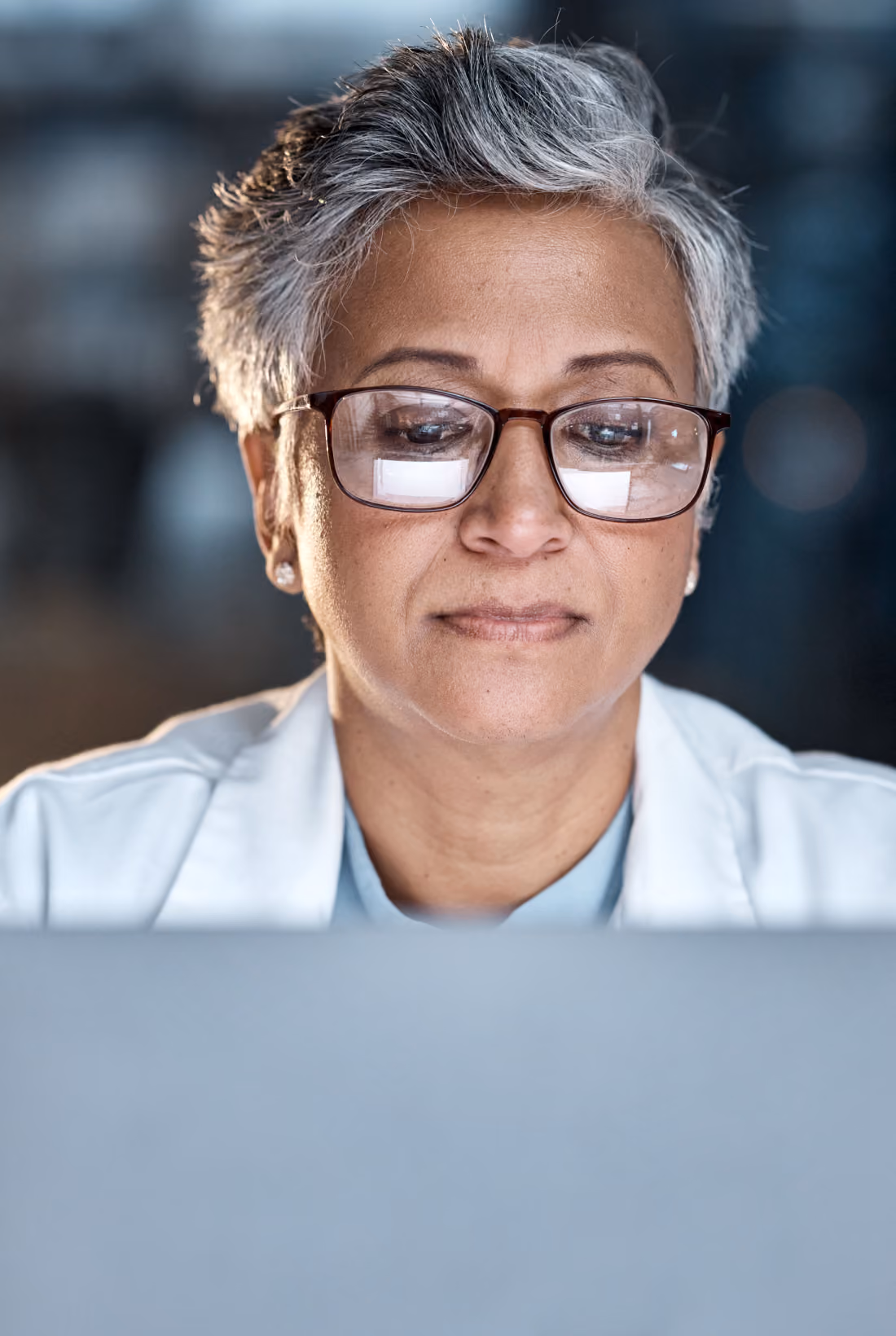 Person wearing glasses working on a laptop at night.