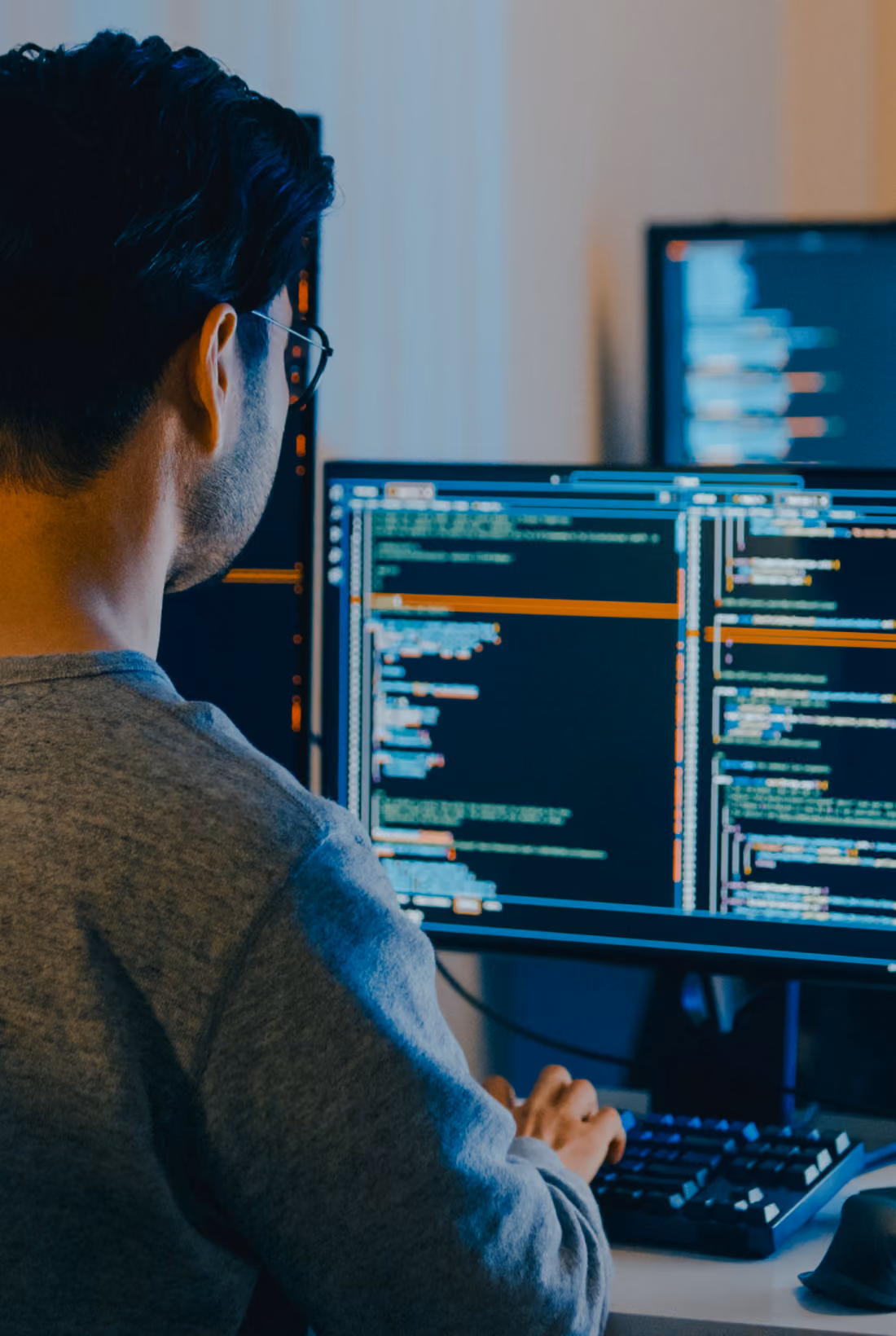 Person coding on multiple computer monitors.