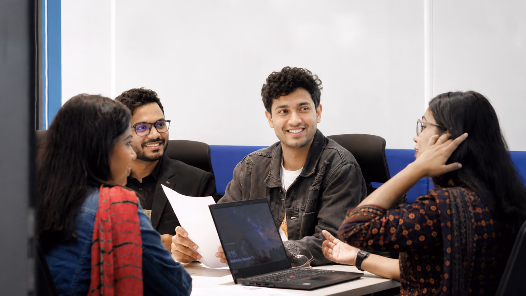 Four people talking around a table in a meeting room.