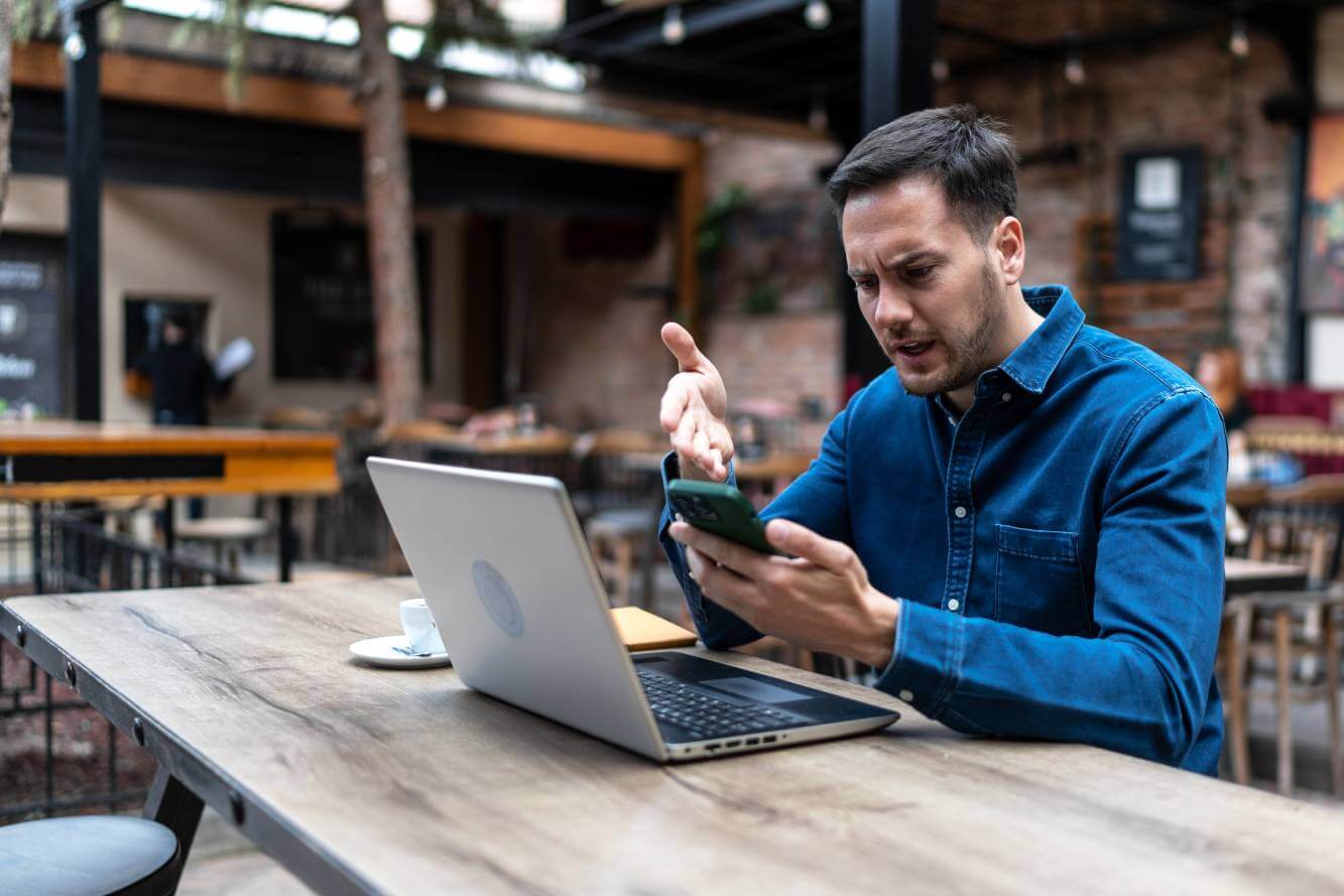 upset man looking at phone text message scam