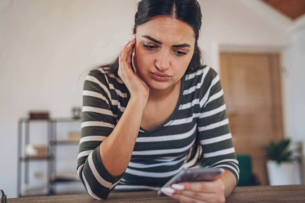 woman looking at phone worried about an employment scam