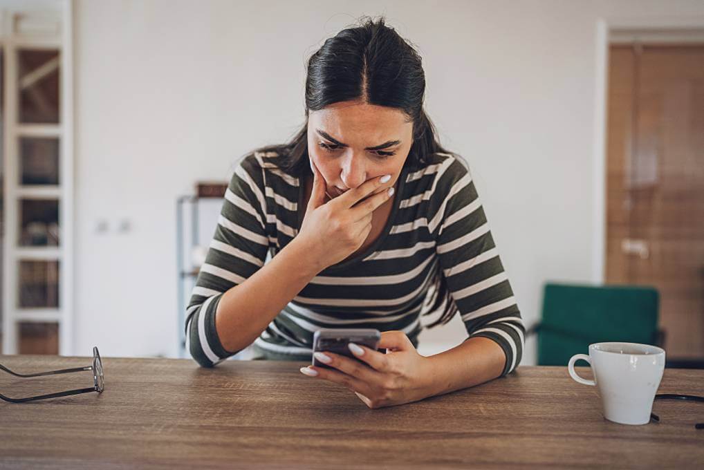 worried woman looking at phone while job hunting due to possible scam