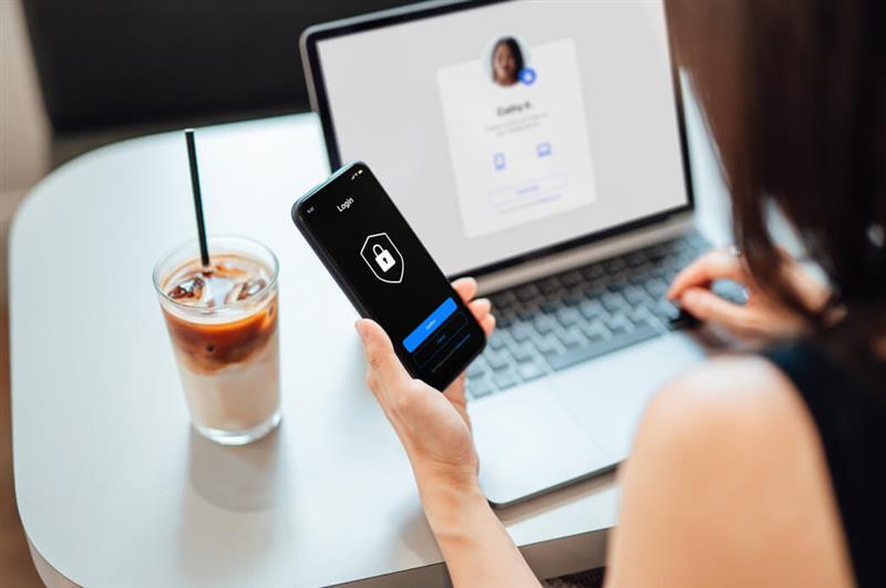 Security shield on phone in hand with computer in background
