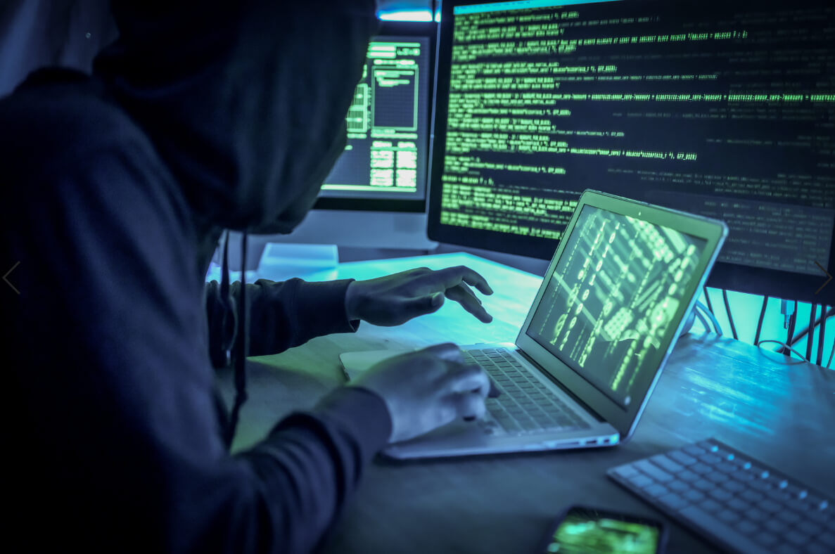 Person with hoodie typing on computer with strange symbols
