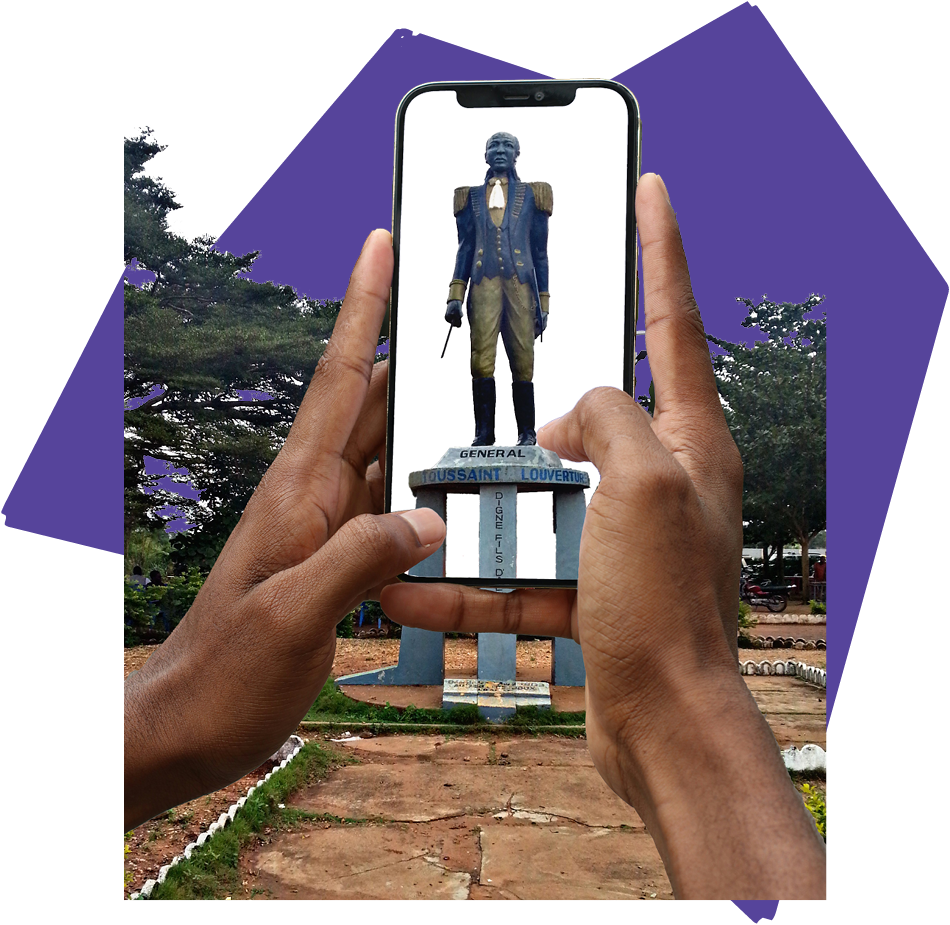 A photograph cutoff of a black person holding up their phone engaging in the augmented reality depiction digitally “installed” a statue of Toussaint L’Ouverture over the physical Christopher Columbus monument