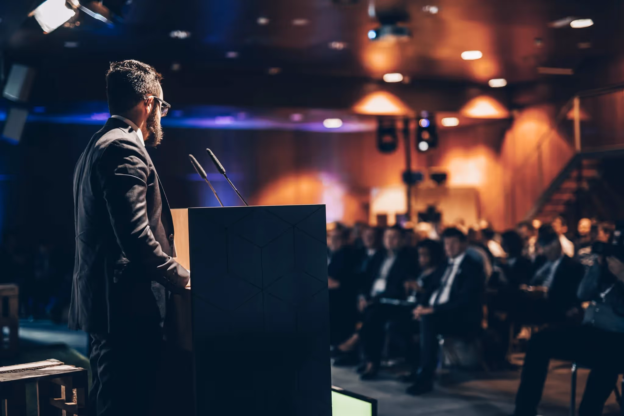 Person speaking at an event in front of a large audience.
