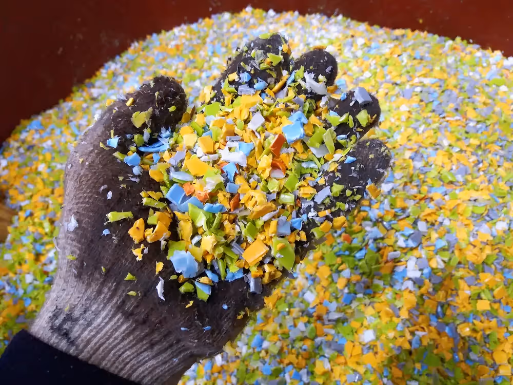 A hand holding pieces of recycled plastic