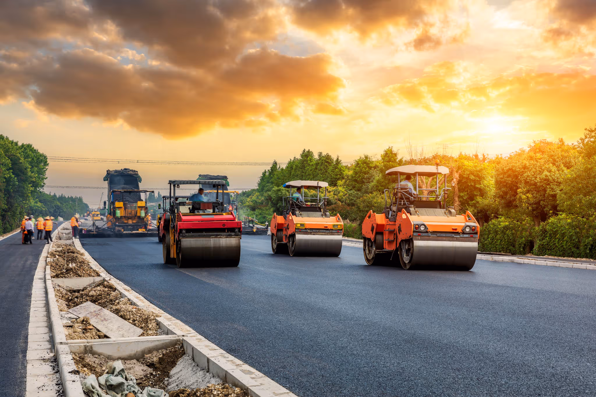 Workers paving an asphalt road using large machinery