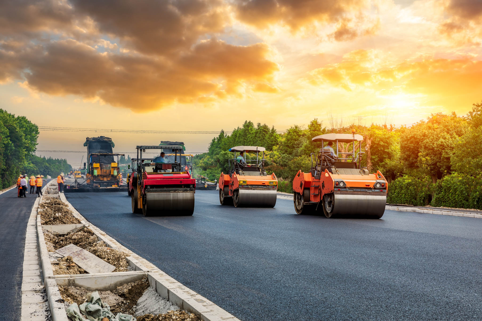Workers paving an asphalt road using large machinery