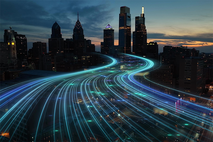 An abstract city landscape with light beams replicating car lights travelling into the city.