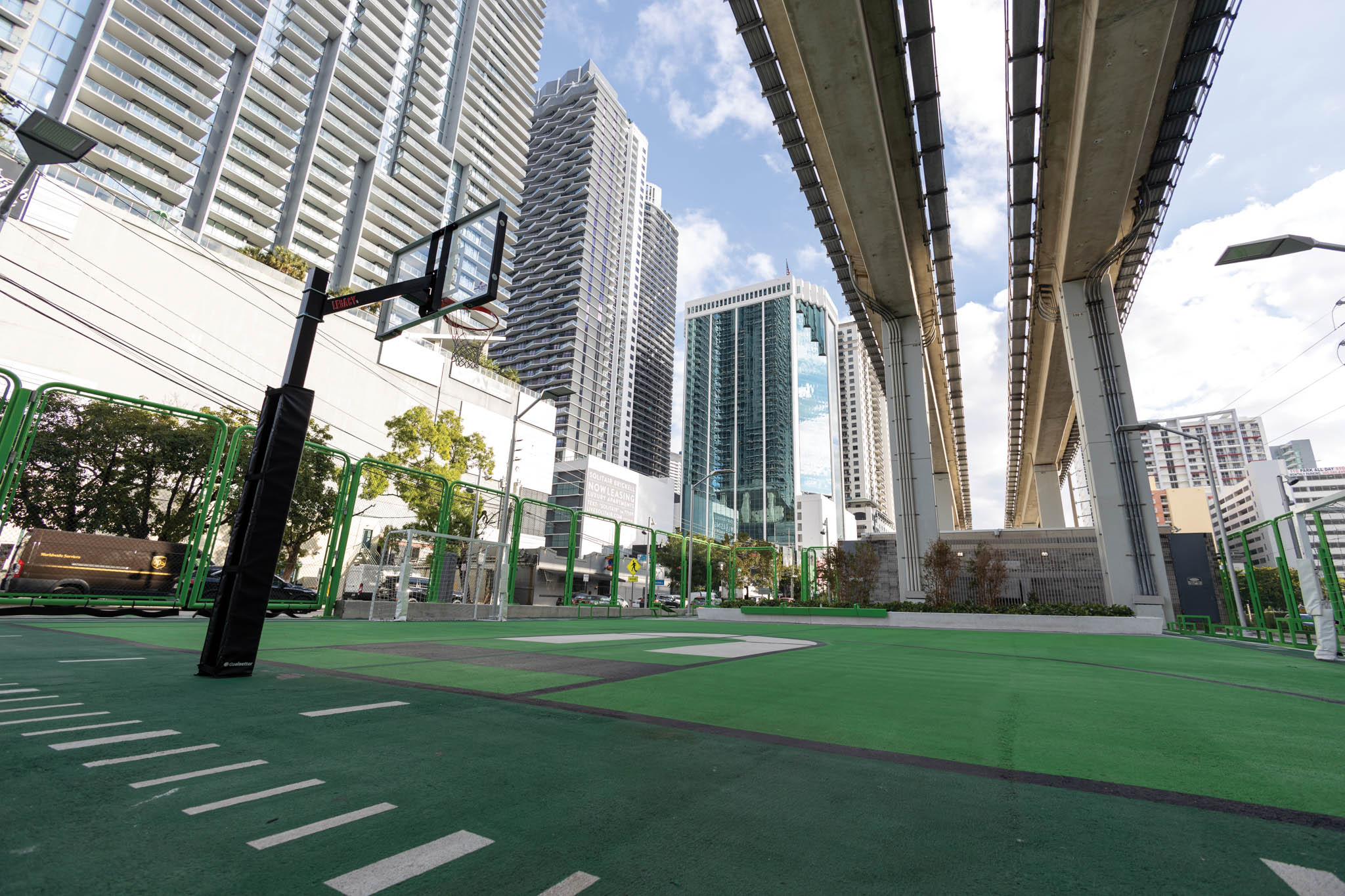 Underneath of a bridge, travelling over a basketball court.
