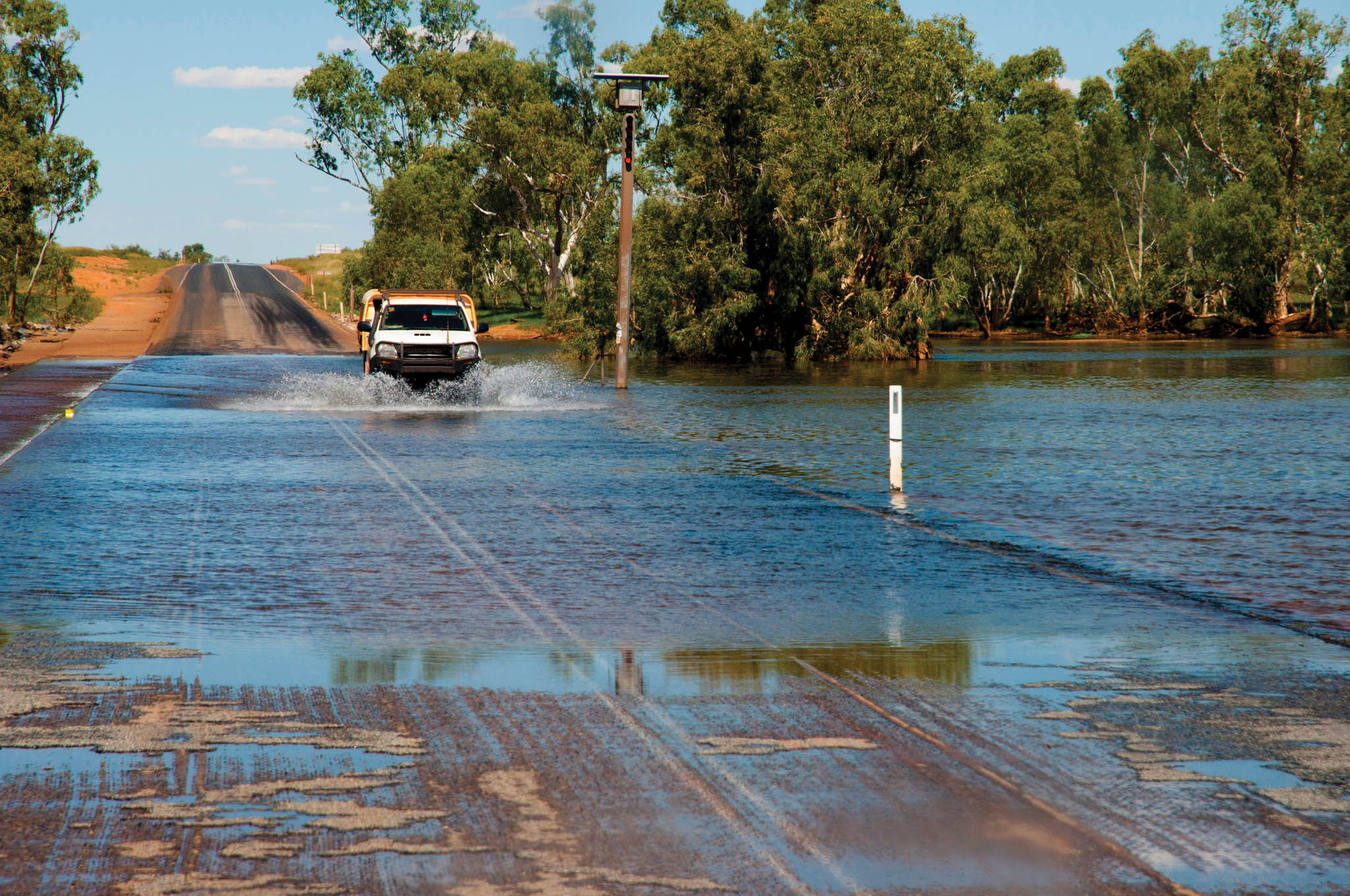 Car driving through water on a flooded road.