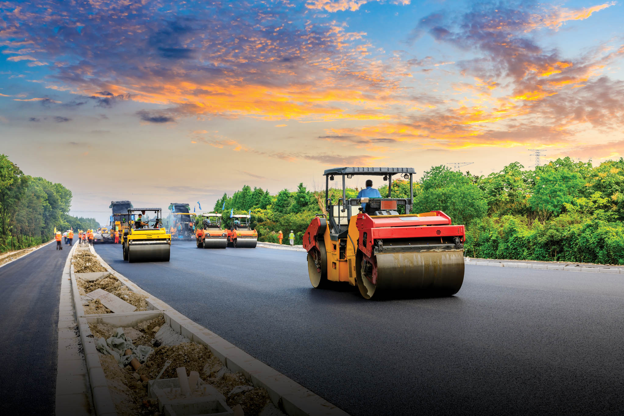 Trucks laying pavement on the road.