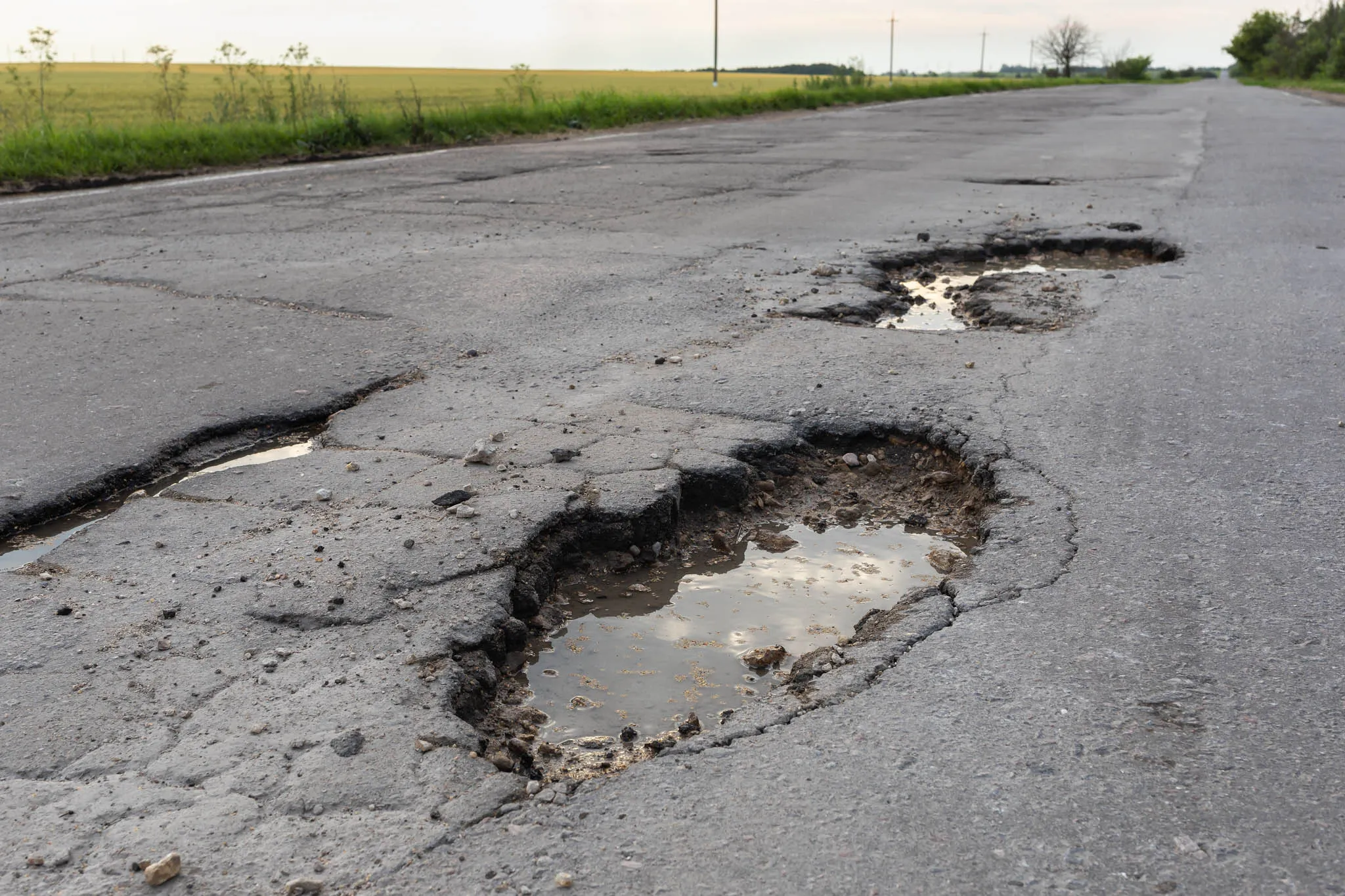 Road with potholes and cracks in the pavement.