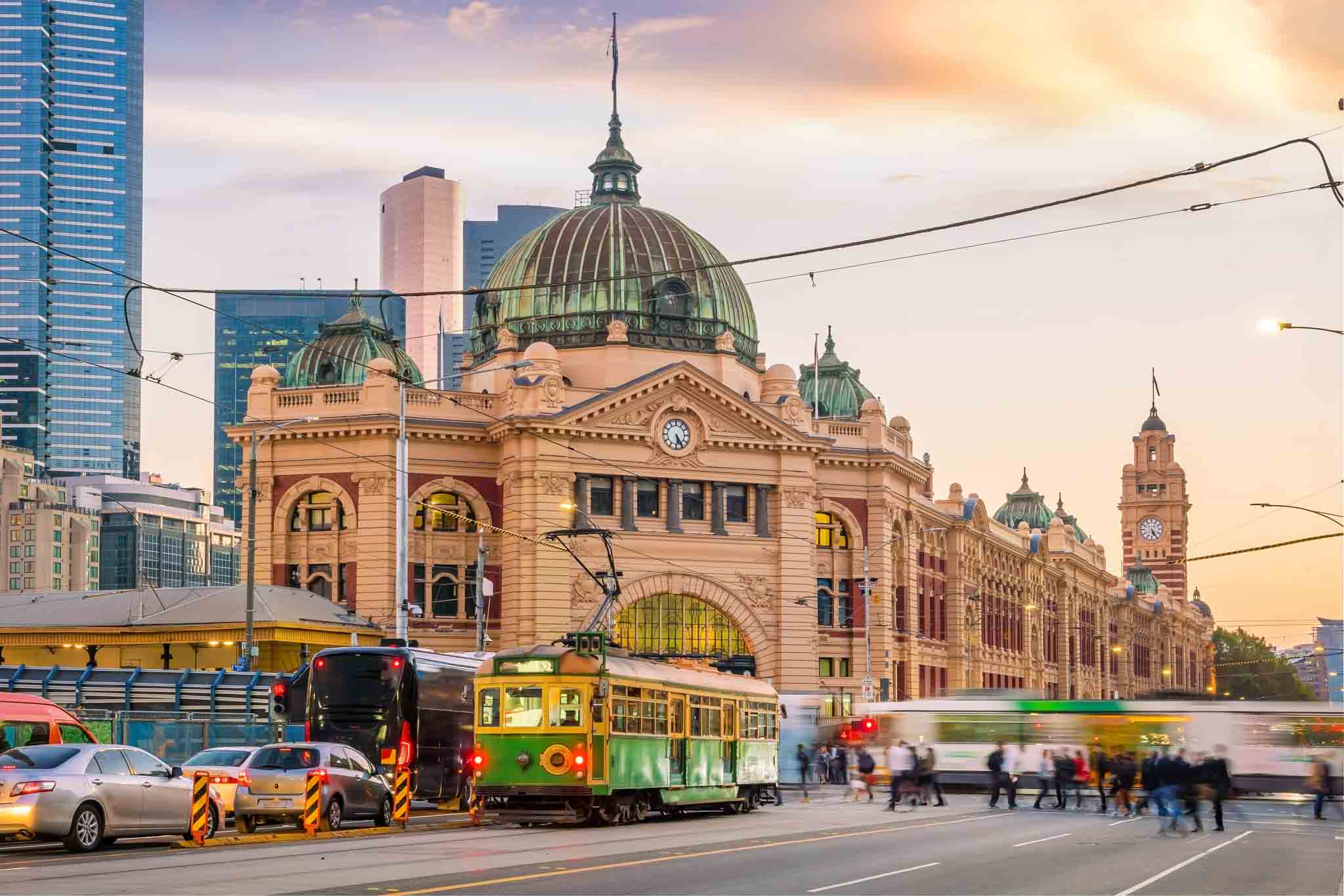 Busy Melbourne street with transport and pedestrians.