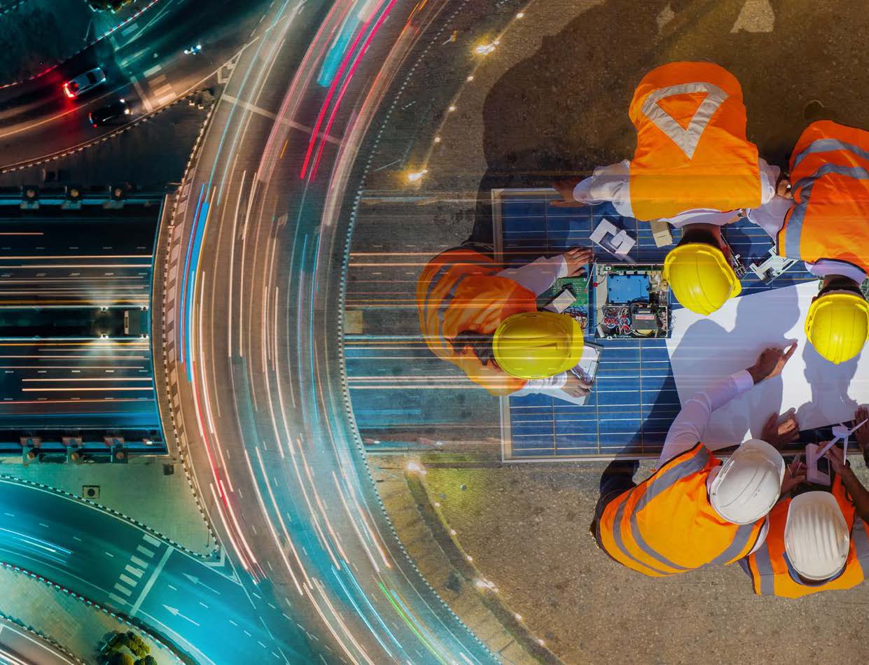 Double exposure of a busy freeway with a team of engineers working at a table.