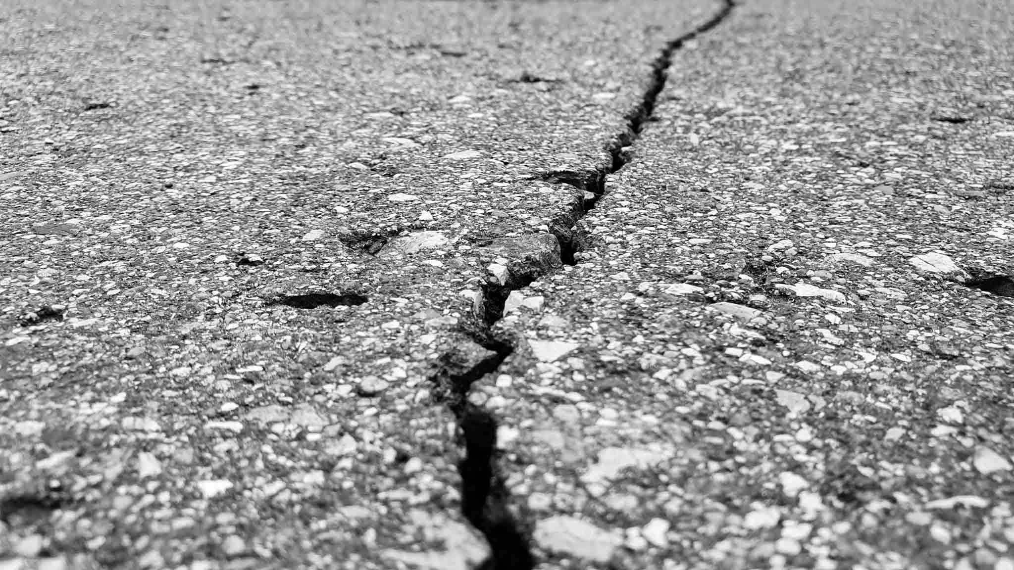 Close up of a pavement with a crack running through it.