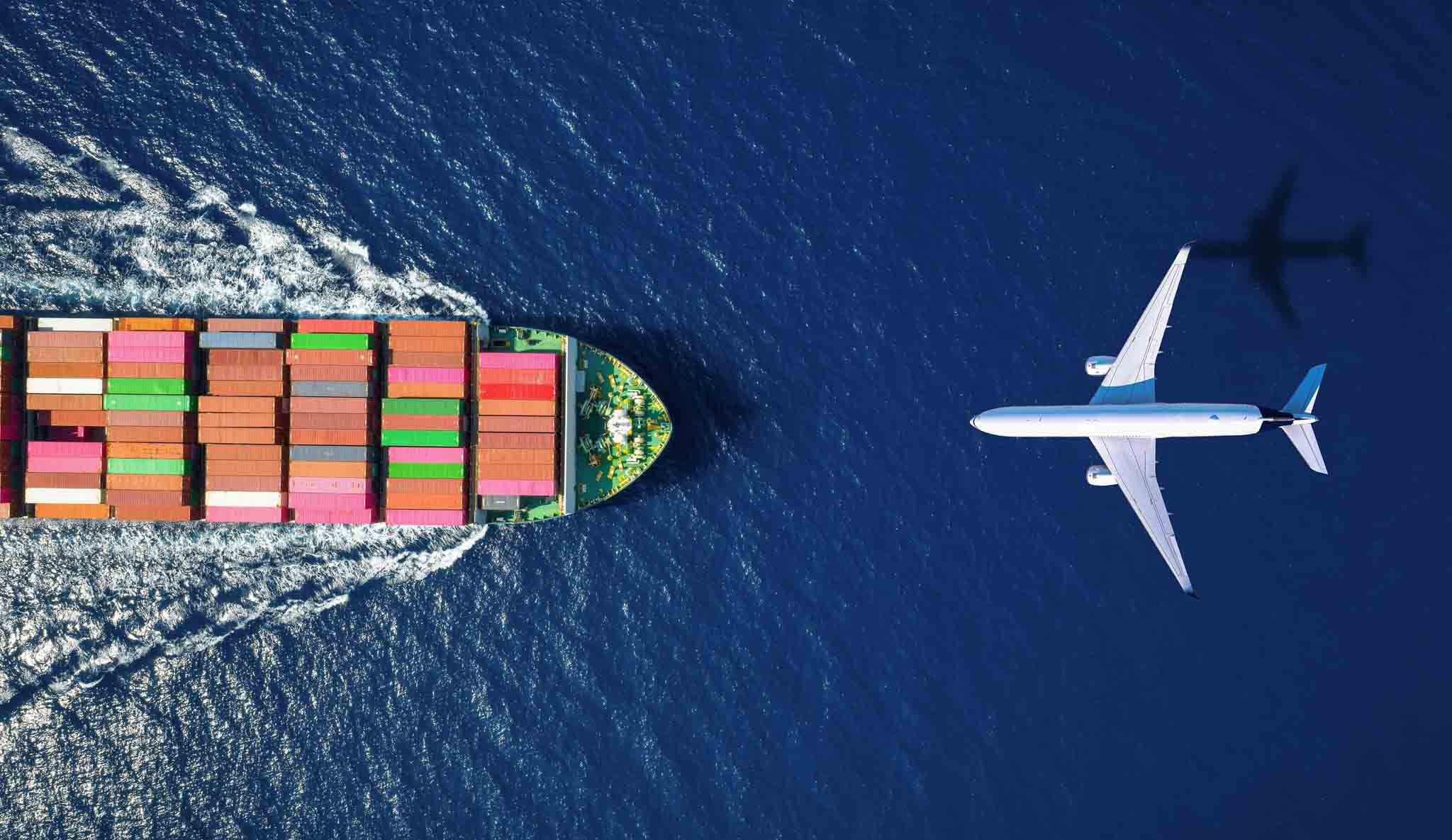 Large ship with containers and a plane travelling over the ocean in opposite directions.