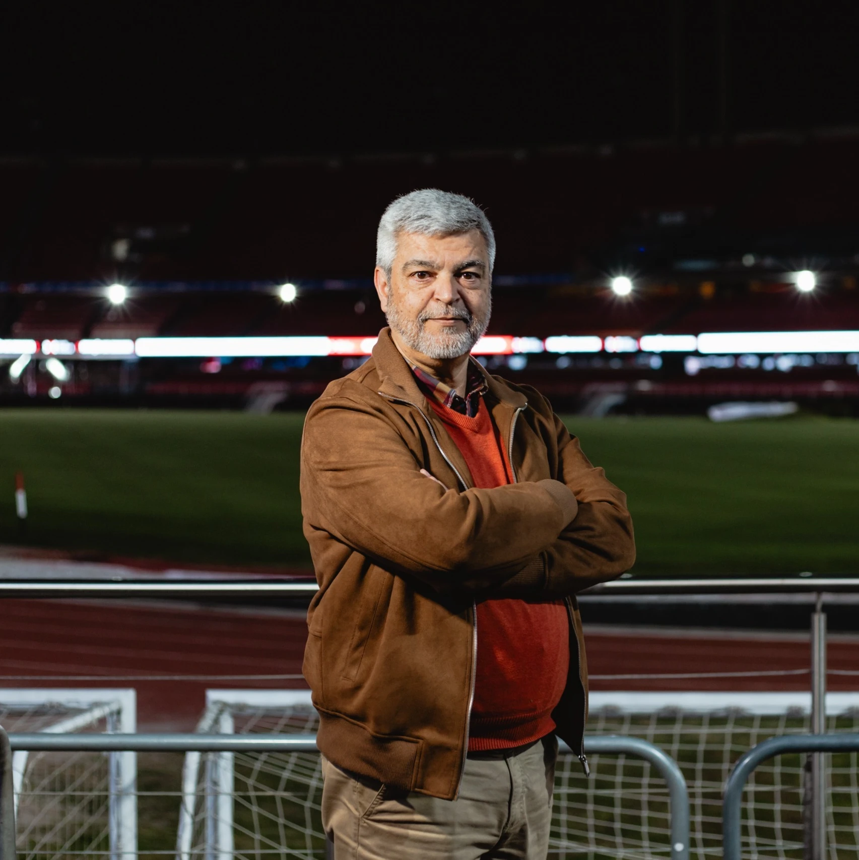 Foto de homem de braços cruzados observando diretamente a câmera