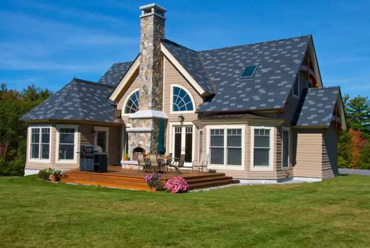 Stylish home with a stone chimney and gray shingle roof.