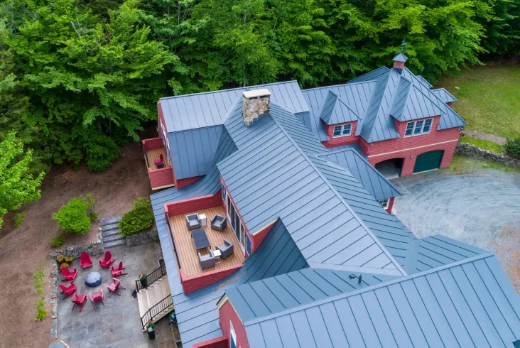 Red house with a modern metal roof and spacious patio area.