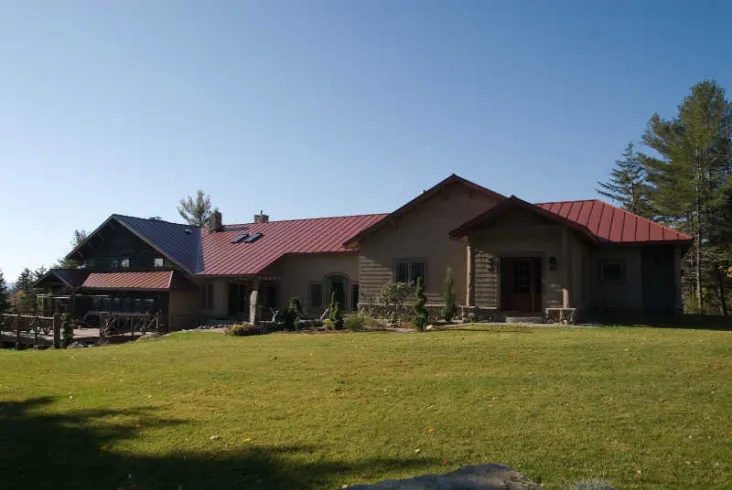 Expansive home with red metal roofs and open lawn.