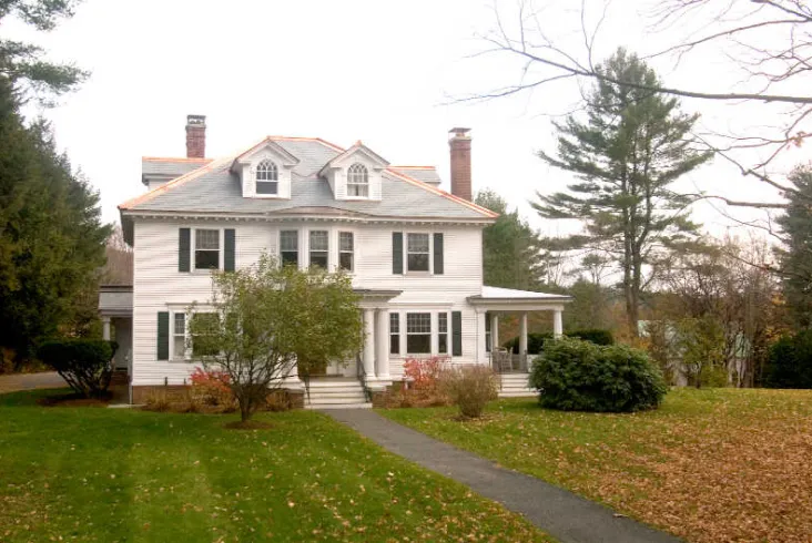 Classic white house with a traditional roof and wide front lawn.
