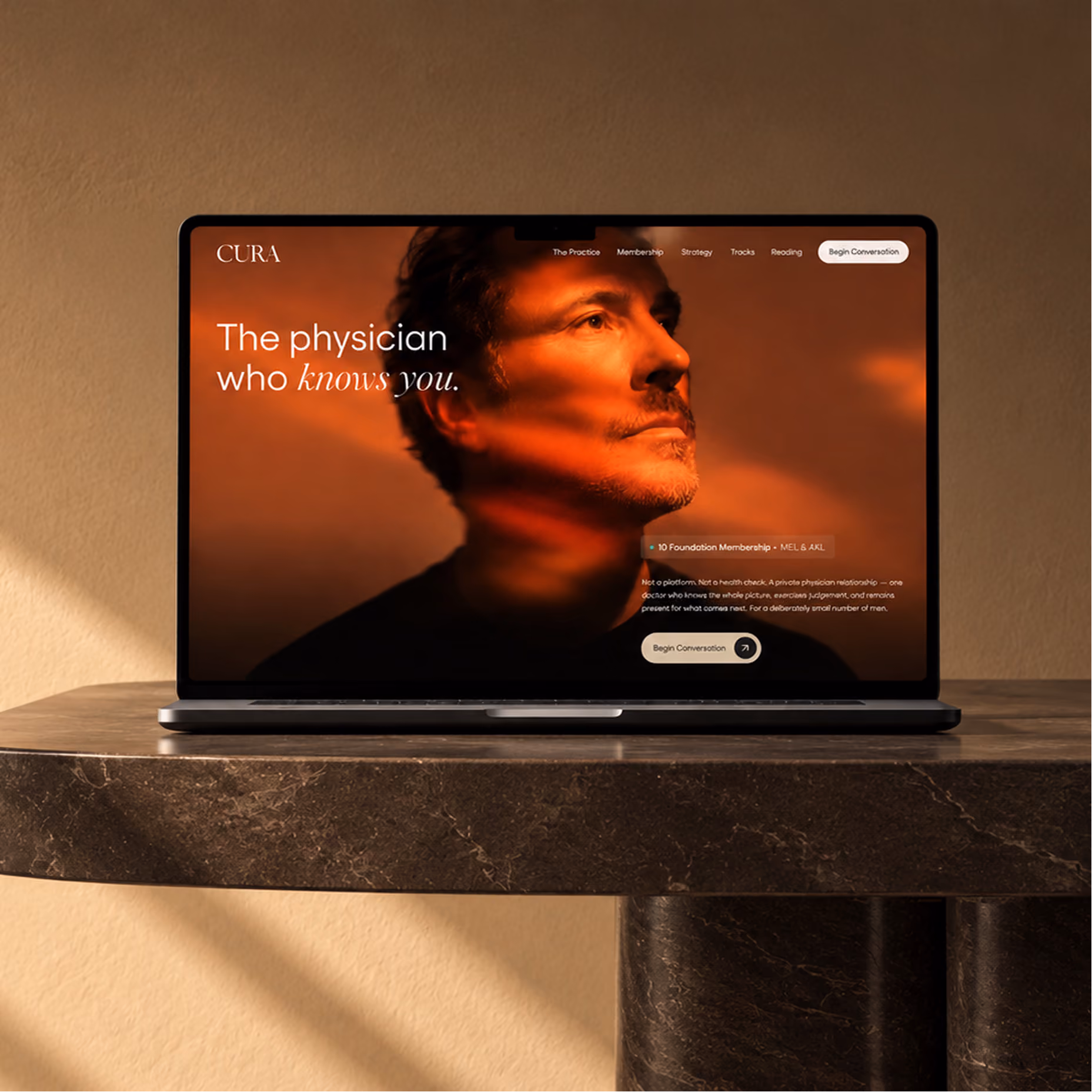 Open laptop on a stone table showing a medical website with an image of a man's face and the headline 'The physician who knows you.'