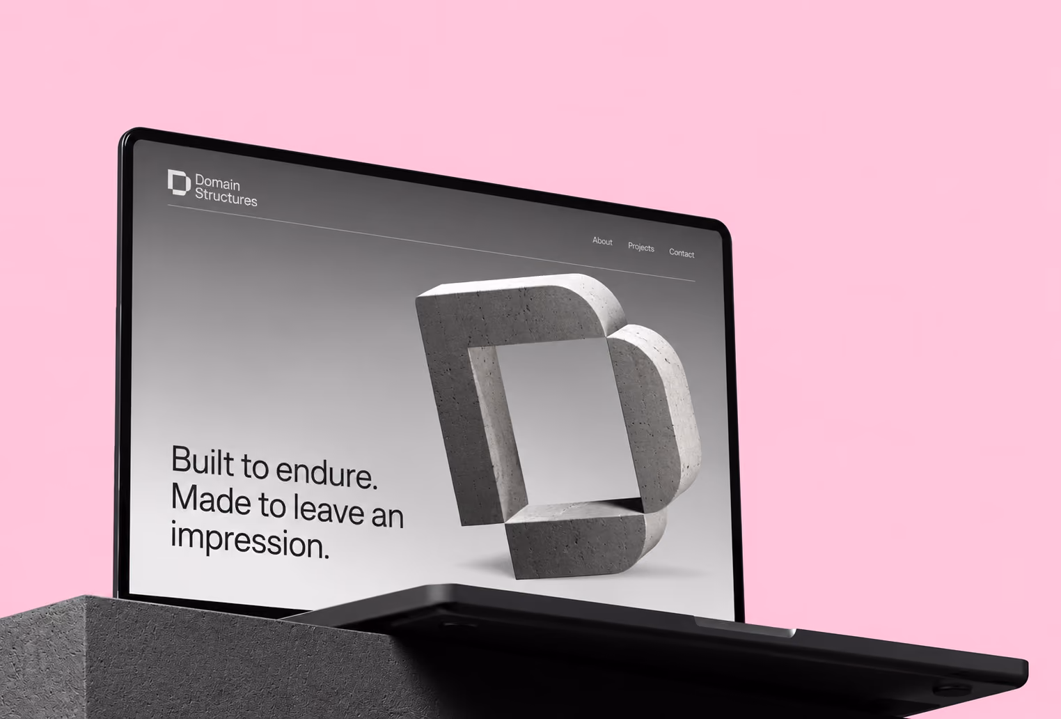 Laptop screen showing a website with a gray concrete 3D logo shaped like an interlocking D and P, text reading 'Built to endure. Made to leave an impression.', and navigation links About, Projects, and Contact, against a pink background.