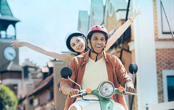 Šťastný pár jazdí na skútri.