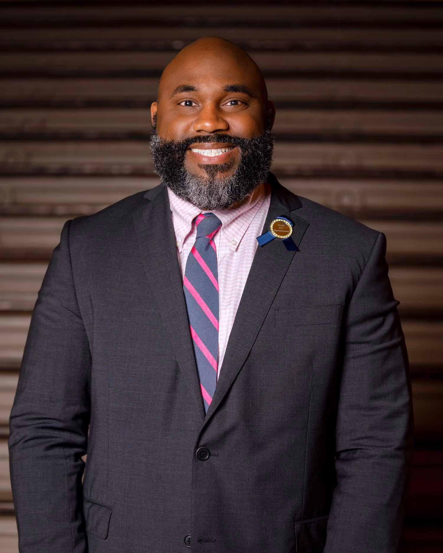 Professional headshot of a smiling man in a gray suit