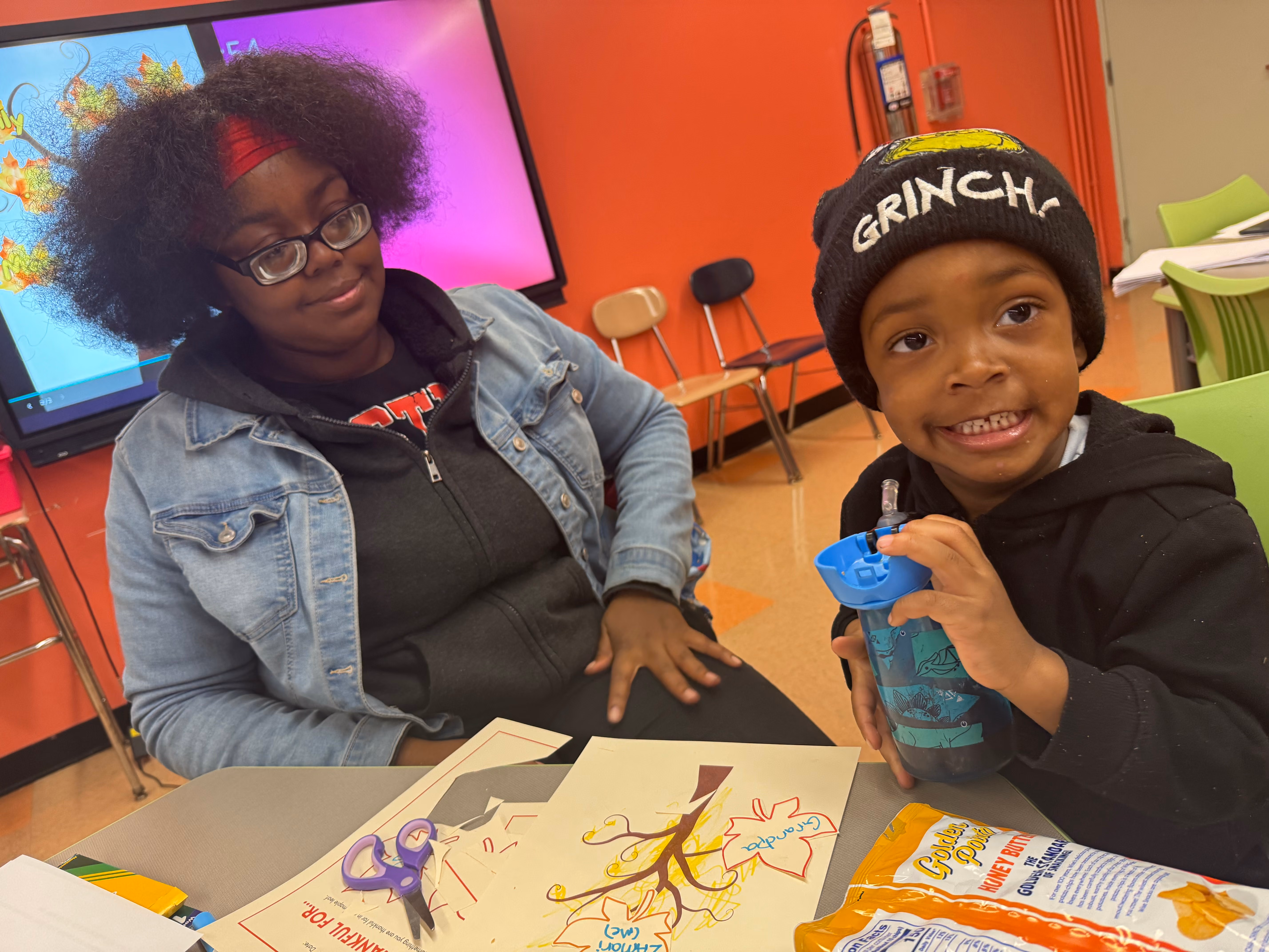 Two students smile while working on a craft activity in class