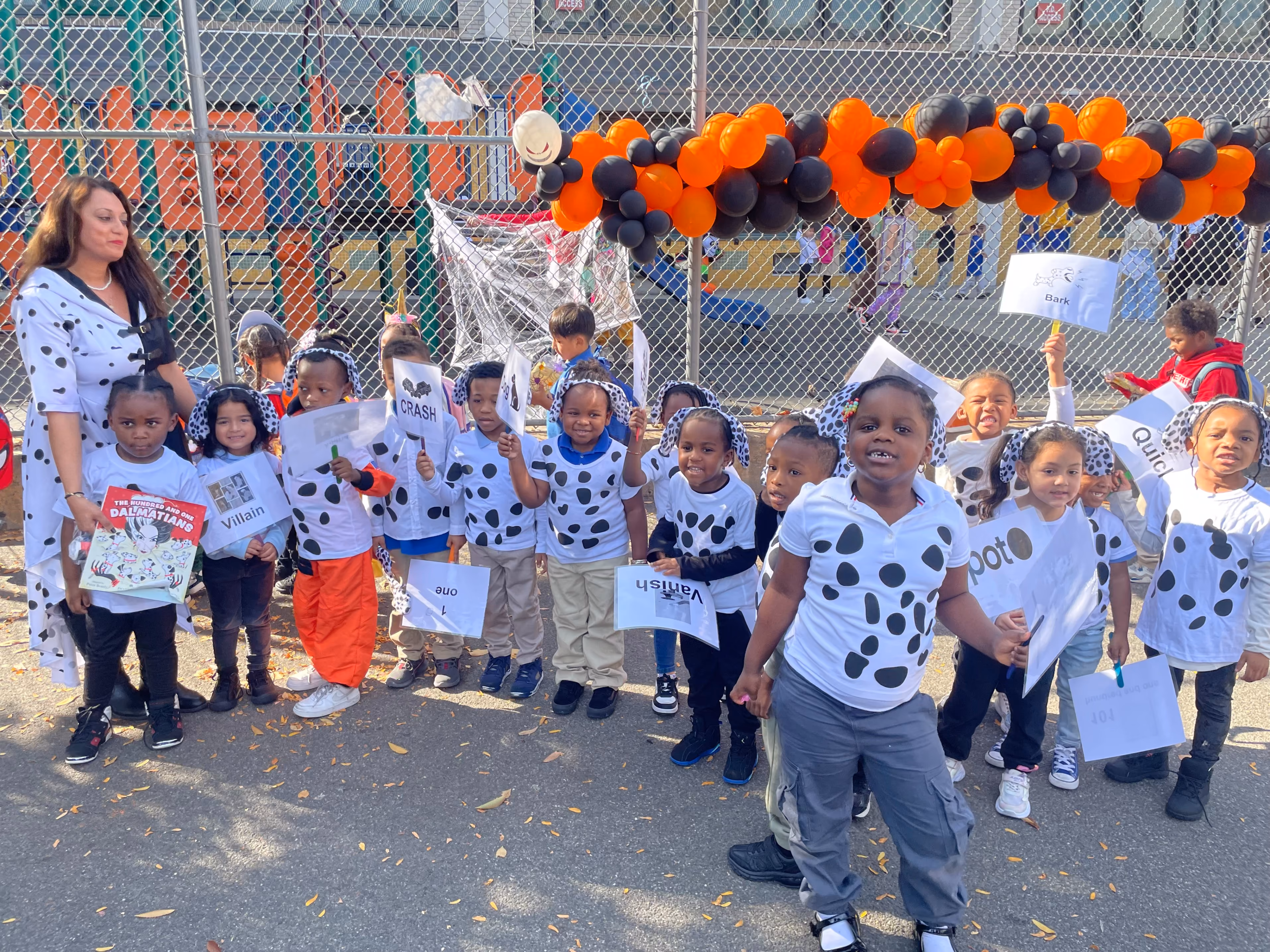 Students in 101 Dalmatians costumes holding vocabulary word signs outdoors