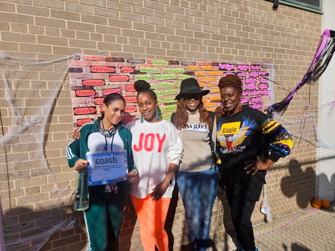 Four women posing outdoors at a school vocabulary word wall event