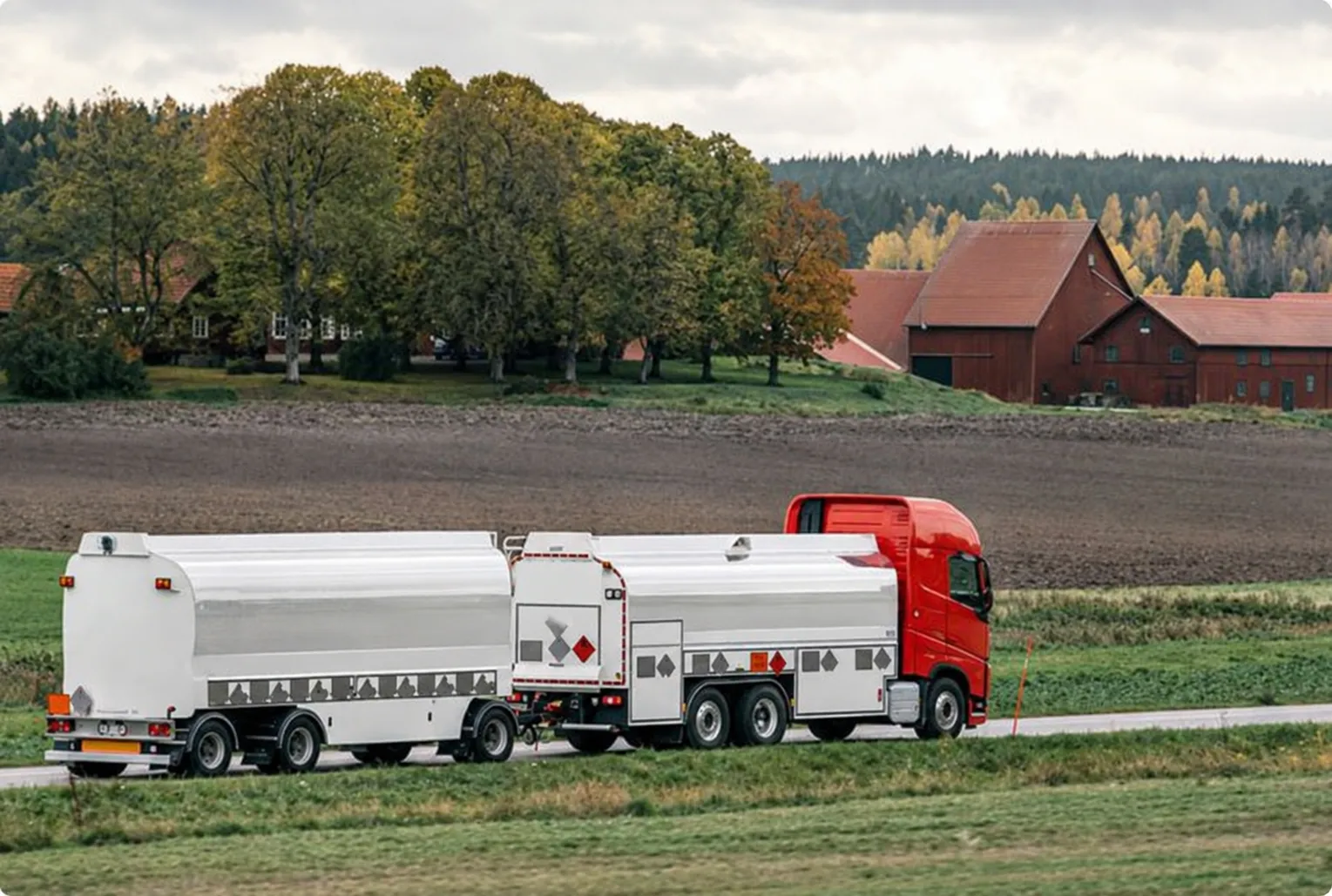 Tankbil för bränsletransport kör på en landsväg genom ett svenskt lantbrukslandskap