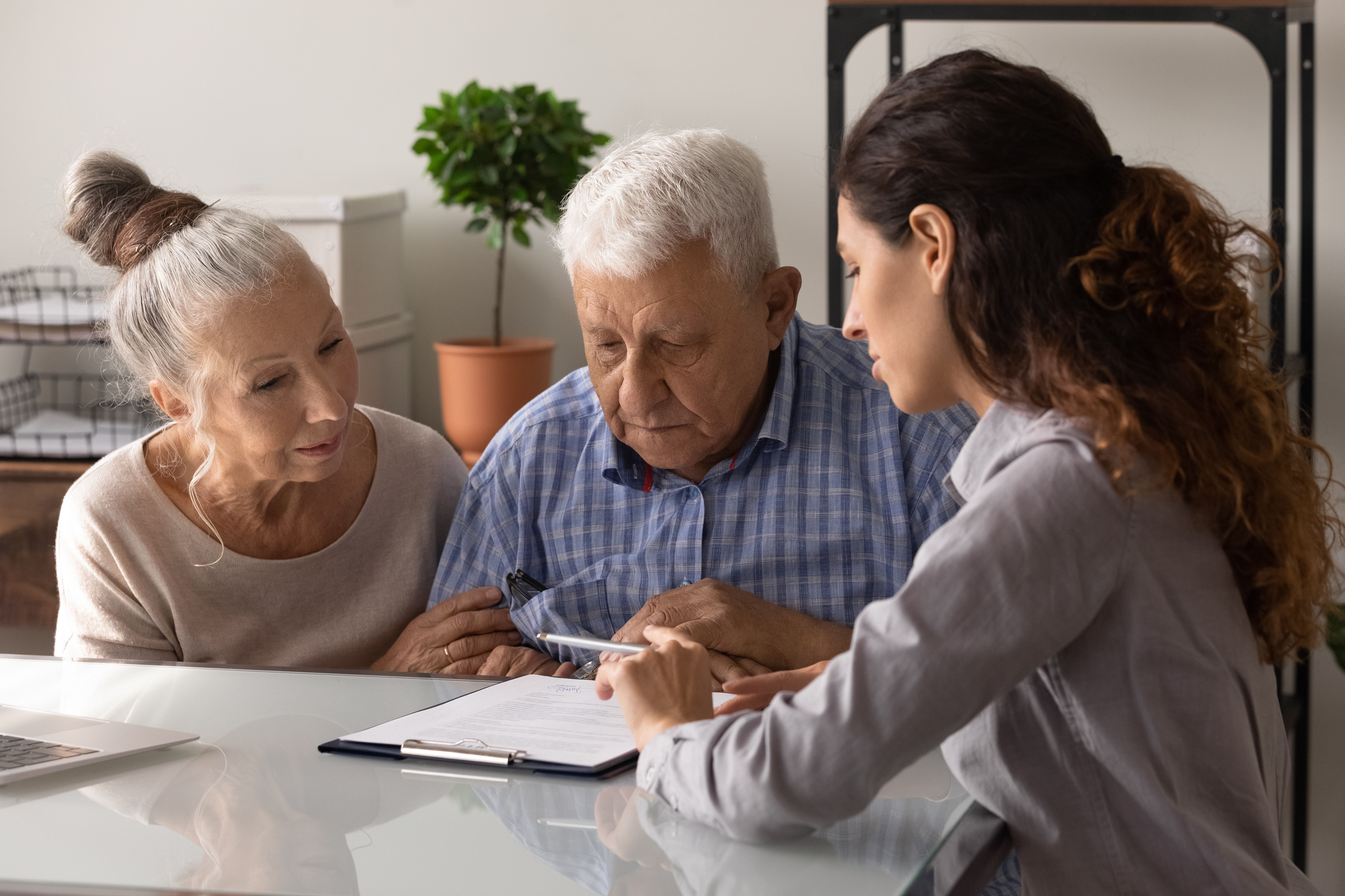 A person assisting elderly couple in understanding a form.